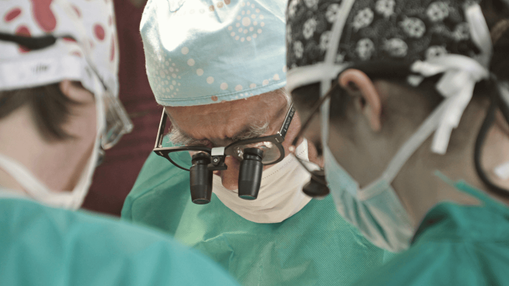 Lead surgeon in the foreground supervising a multidisciplinary team during complex surgery in a hospital setting