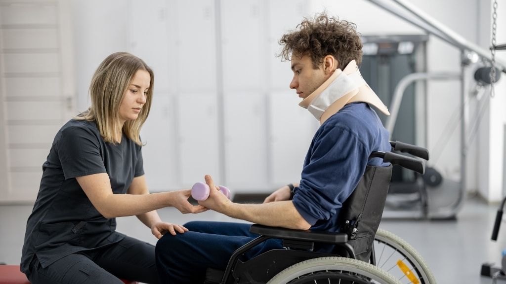 Patient in a wheelchair receiving personalised rehabilitation from a therapist